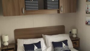 A bed with two pillows, a wooden headboard, and two bedside tables with lamps. - SeaSalt -Low cost accommodation, Harlyn Sands (Padstow)