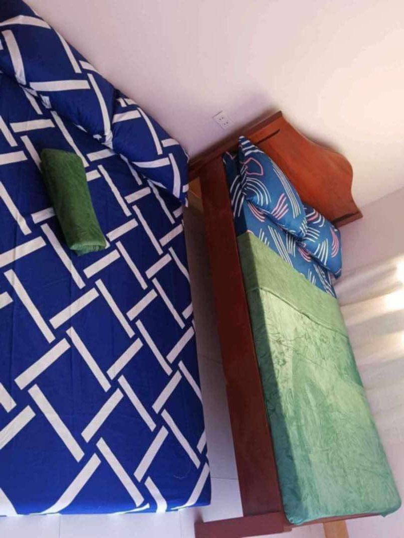 Deux lits avec une literie à motifs : l’un avec un motif bleu et blanc, et l’autre avec un motif vert et bleu.