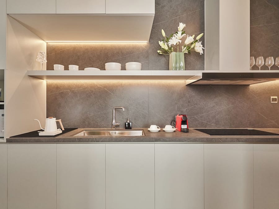 A modern kitchen with a built-in sink, a coffee maker, and a vase with flowers on the countertop.