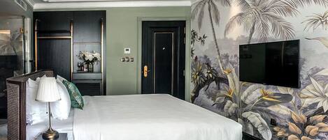 A hotel room with a large bed, a TV mounted on the wall, and a tropical-themed mural.