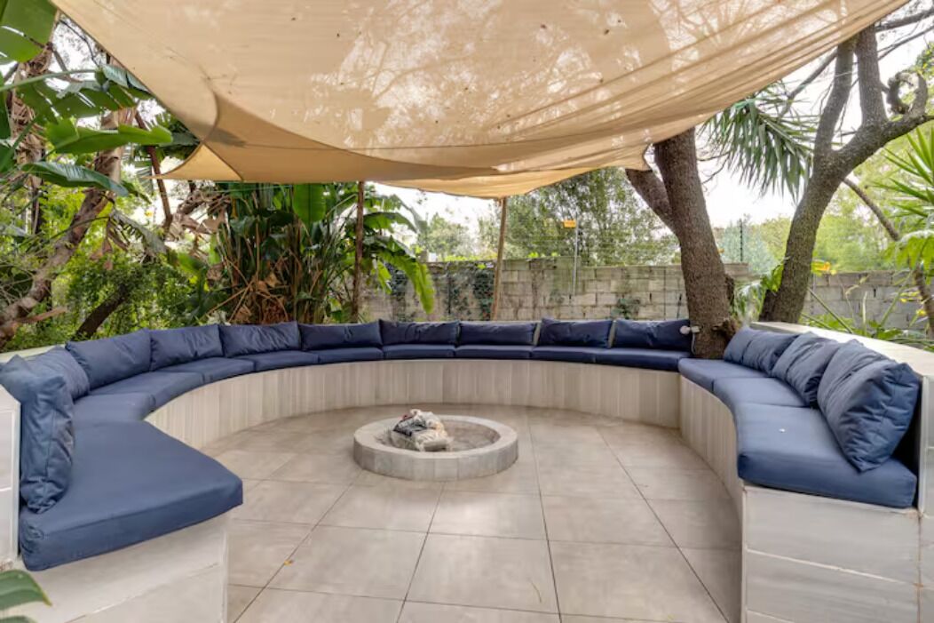 A semi-circular outdoor seating area with blue cushions and a central fire pit.