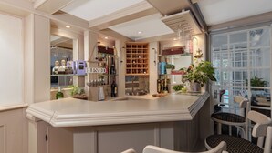 A kitchen with a bar area, shelves with bottles, a wine rack, and a window with a view.