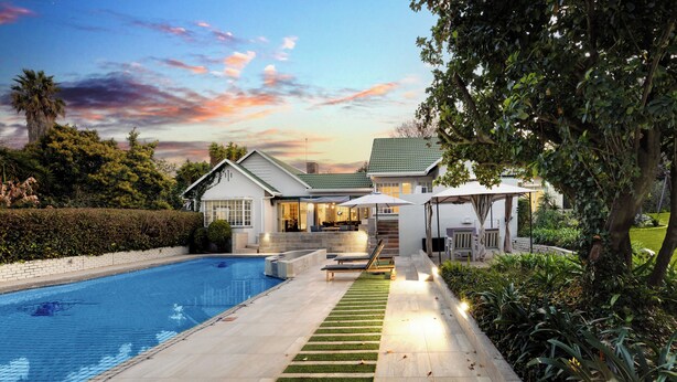 A modern house with a swimming pool, a well-maintained lawn, and a patio area.