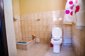 A small bathroom with a toilet, a shower, and a tiled floor. - Bujumbura Hotel and appartment (Bujumbura)