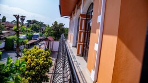 A balcony with a metal railing overlooking a parking area and greenery.