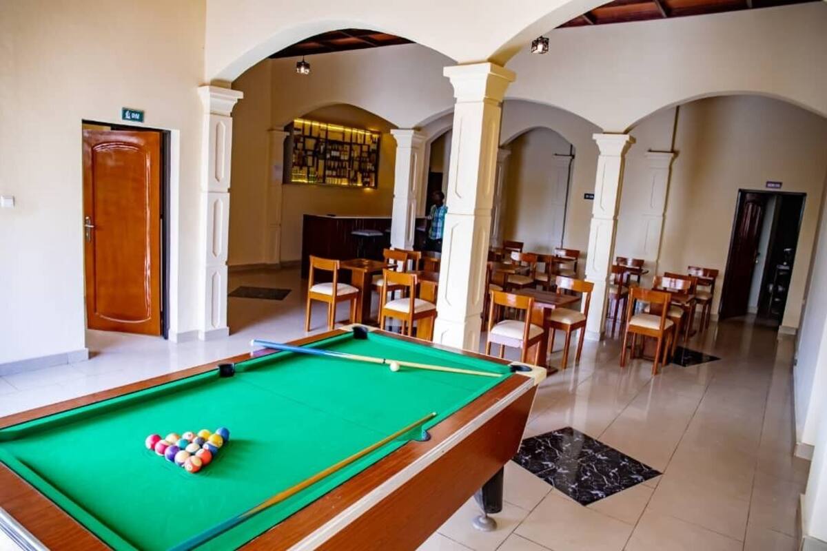 A pool table with balls, a bar area, and seating arrangements in a room with arches.