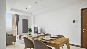 A modern dining area with a wooden table set for four, surrounded by grey upholstered chairs.