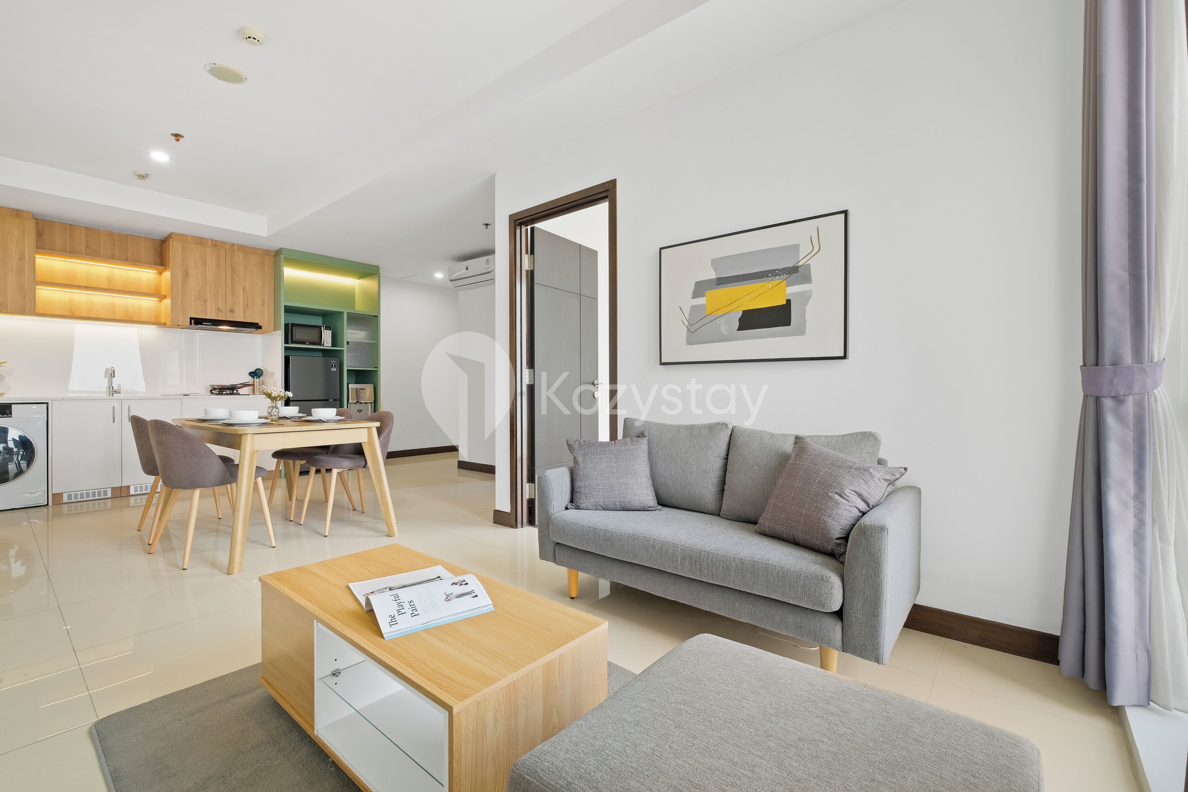 A modern living room with a grey sofa, a wooden coffee table, and a dining area with a table and chairs.