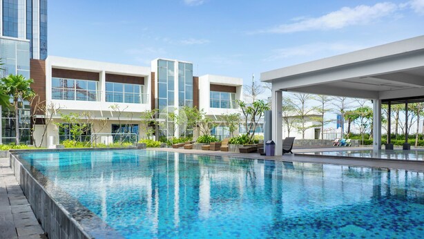 A modern hotel with a large indoor swimming pool, outdoor seating areas, and a view of the surrounding buildings.