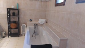 A bathroom with a bathtub, a shelf with toiletries, and a window. - El Nido BY LAVILLA25 Noaillan (Noaillan)