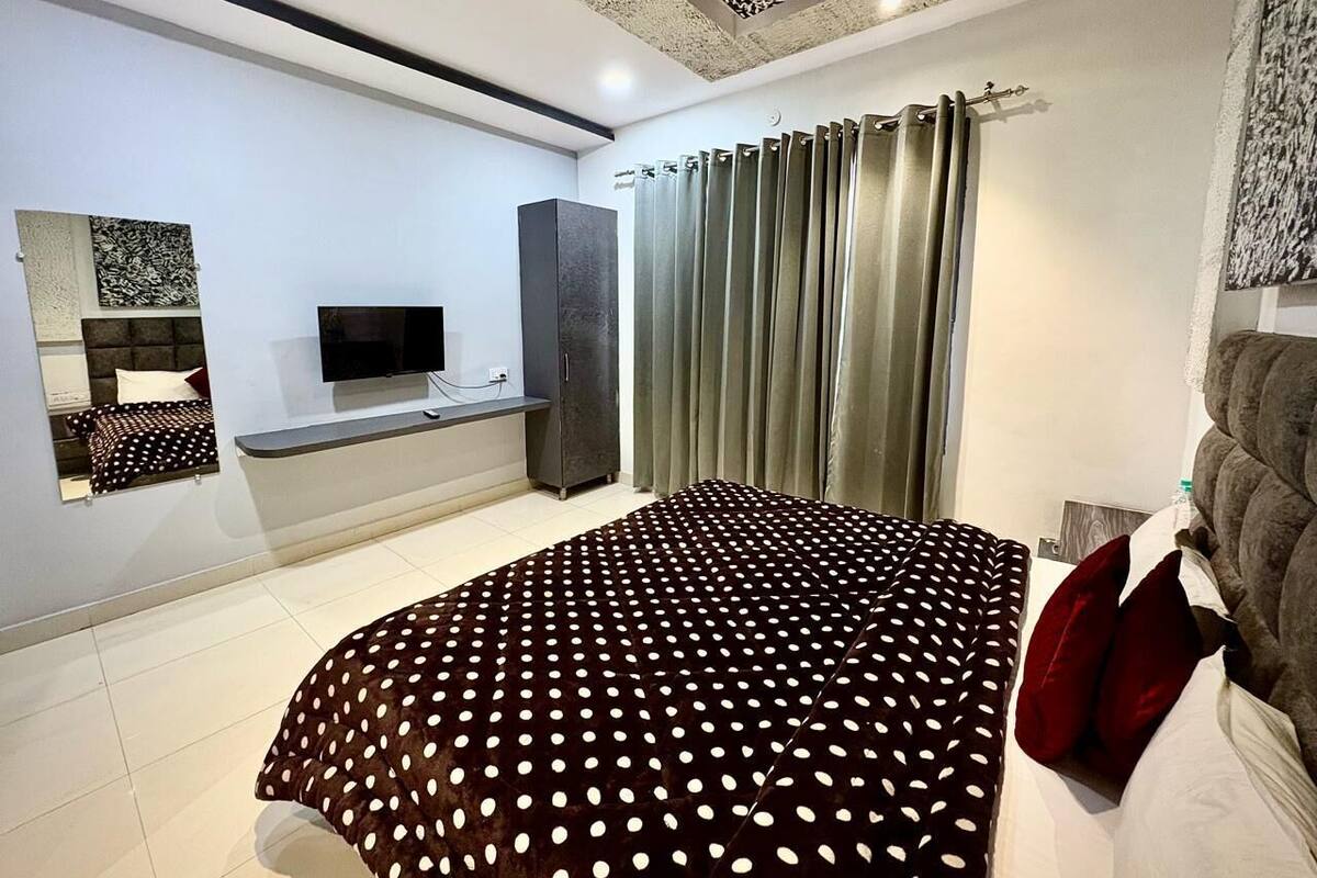 Un dormitorio moderno con una cama grande, un televisor de pantalla plana, un armario y una ventana con cortinas.