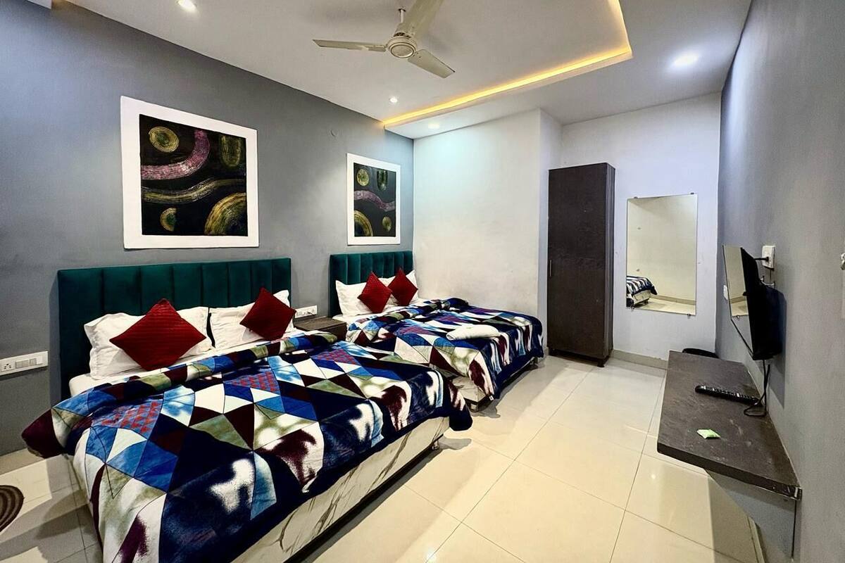 Una habitación de hotel moderna con una cama grande, un escritorio, un televisor y obras de arte en las paredes.