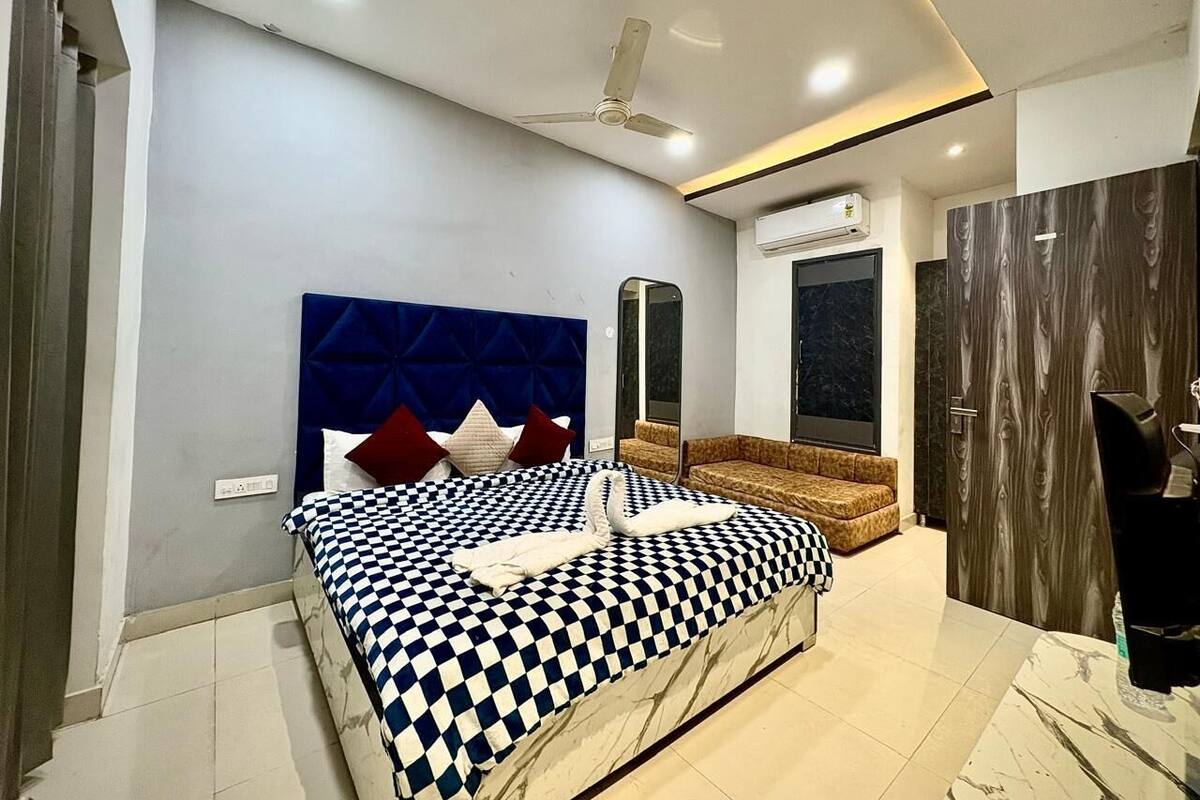 Un dormitorio moderno con colcha a cuadros, cabecera tapizada en azul y sofá marrón.