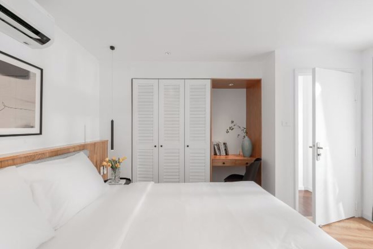 Un dormitorio con cama, armario, escritorio y puerta.