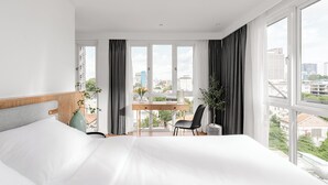 Una habitación de hotel moderna con una cama grande, un escritorio y vistas a la ciudad.