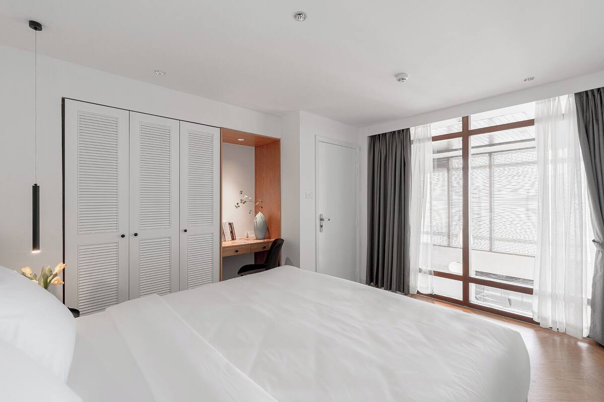 A bedroom with a large bed, a desk, and a wardrobe.