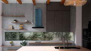 Una cocina moderna con una isla grande, vigas de madera y vistas al exterior.