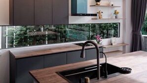 Una cocina moderna con una isla central, armarios oscuros y un ventanal con vistas a zonas verdes.