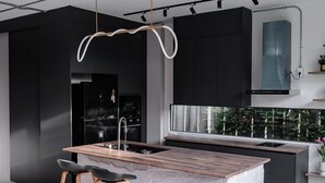 Una cocina moderna con una isla central, iluminación colgante y vistas al exterior.