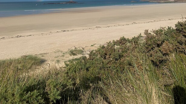 A beach with a rainbow, clear sky, and distant rocky formations. - VILLA GRAVELOUP family vacation home, close to the sea and beaches (Erquy)