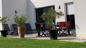 A modern house with a patio area featuring outdoor furniture and potted plants. - VILLA GRAVELOUP family vacation home, close to the sea and beaches (Erquy)