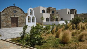 A modern building with a stone facade, a bell tower, and a white entrance. - Emerald Tinos (Tinos)