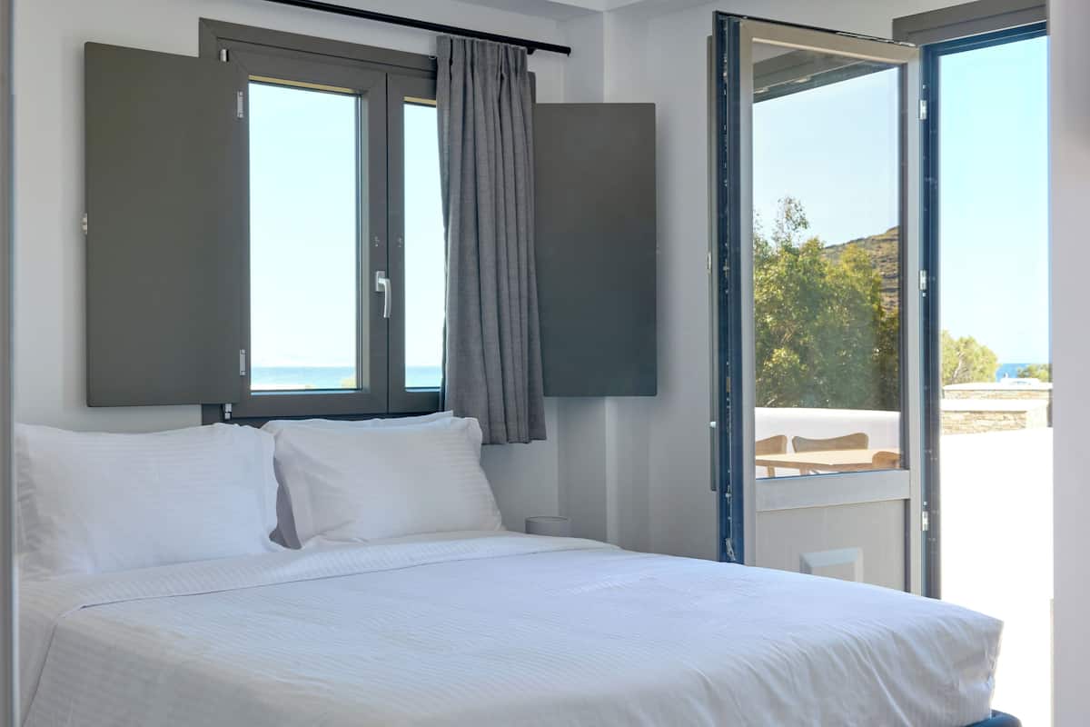 Un dormitorio con cama, ventana con cortinas y vistas al exterior.
