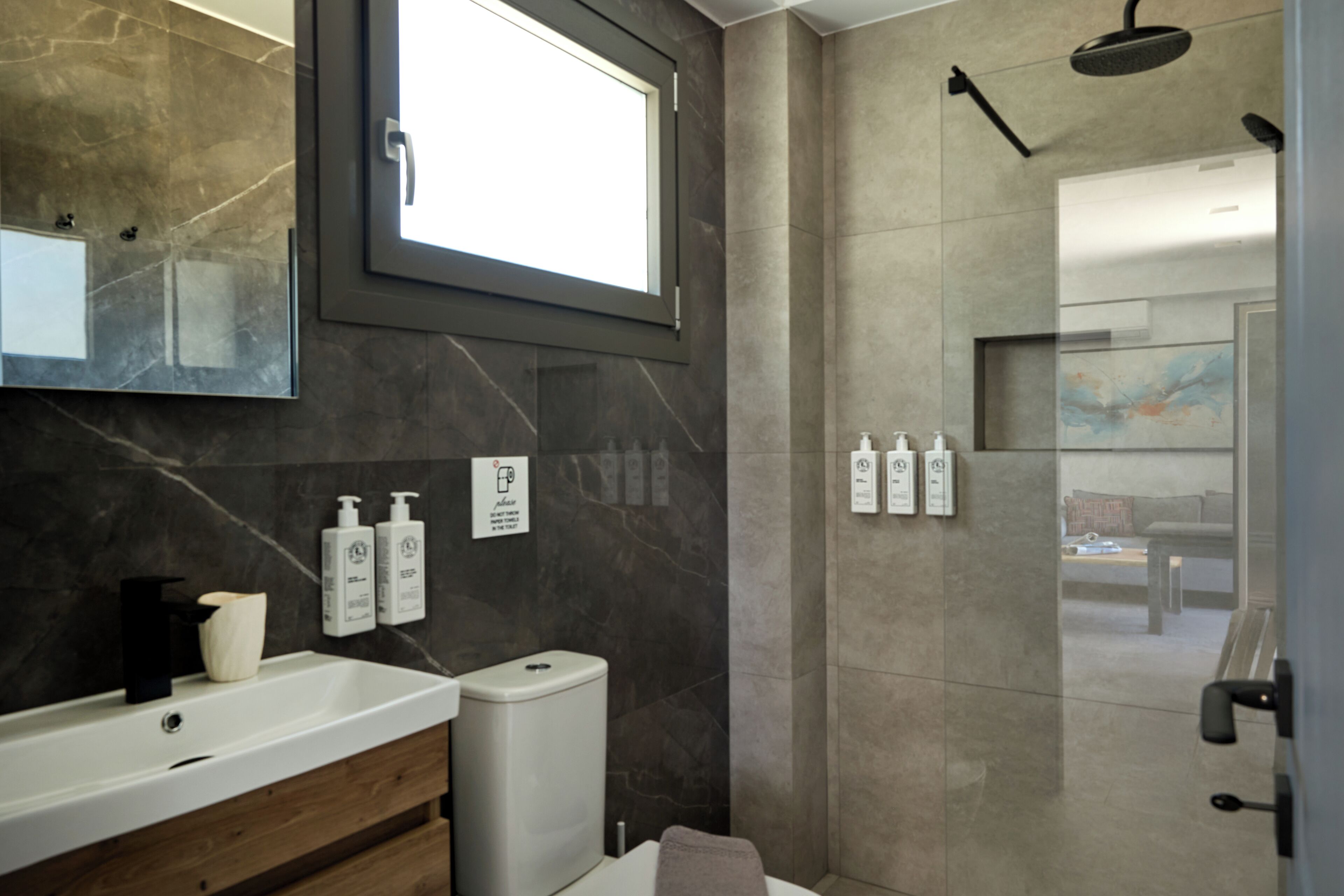 Une salle de bain moderne avec un grand miroir, un lavabo, des toilettes et un espace douche.