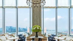 Un amplio salón con vistas a la ciudad, grandes ventanales y muebles modernos.