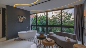 Un baño moderno con una bañera independiente, un amplio ventanal con vistas a la vegetación y un diseño contemporáneo con una paleta de colores neutros.