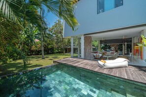 A modern house with a swimming pool, wooden deck, and outdoor furniture. - Villa Art (Canggu)