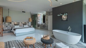 Un dormitorio moderno con una cama grande, una bañera y un baño con baldosas estampadas y un adorno en la pared.