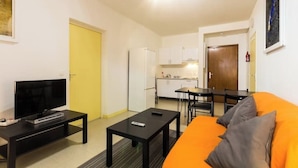 A compact living space with a TV, a sofa, a dining table, and a kitchen area. - T3 in green Grenoble city center (Grenoble)