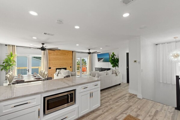 A modern kitchen with a central island, white cabinetry, and a built-in microwave.