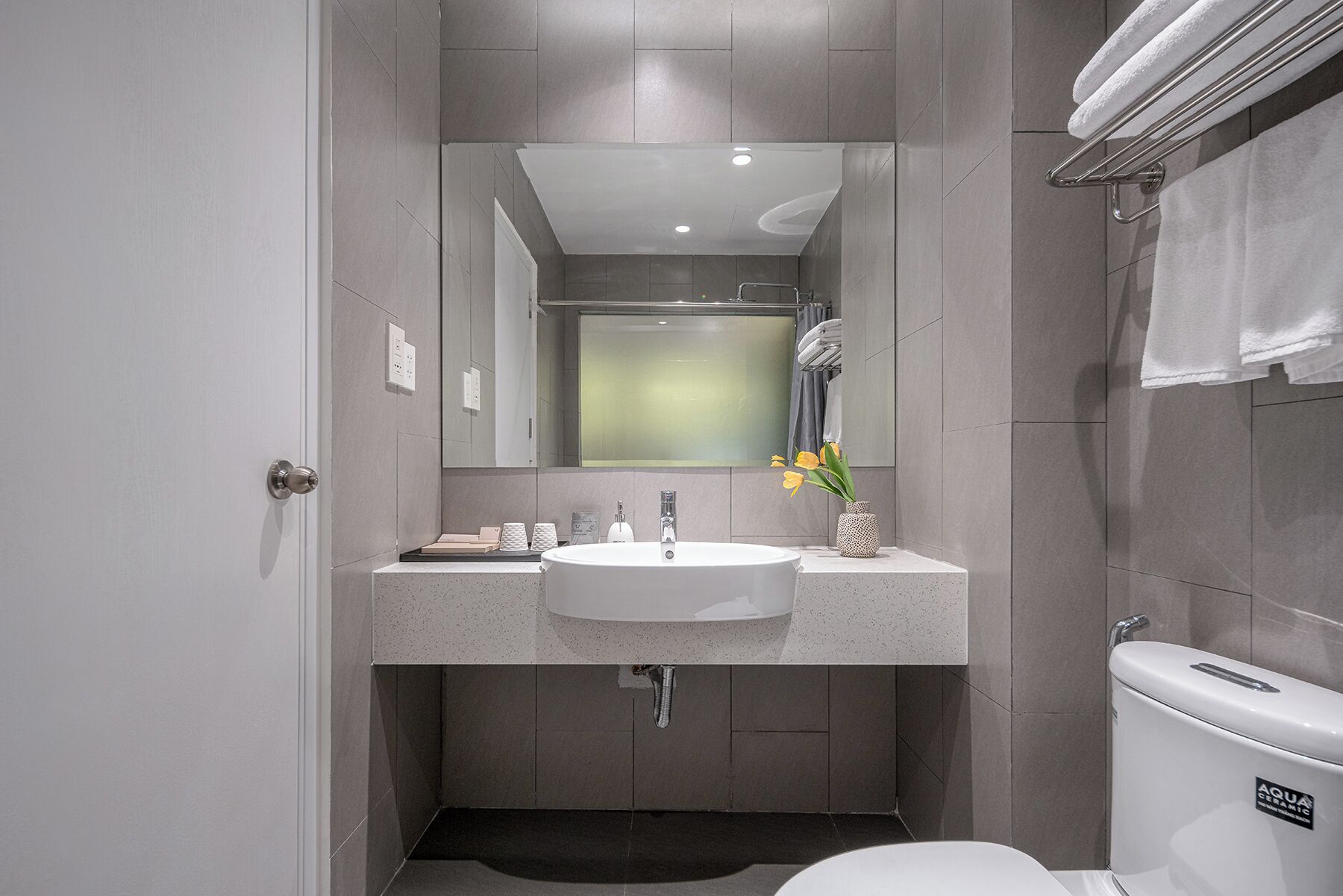 A modern bathroom with a white sink, mirror, and toilet.