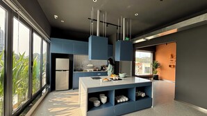 A modern kitchen with a large island, blue cabinets, and a view of greenery outside. - M Village Hotel Lý Tự Trọng, a brand of Modern Village Lifestyle (Ho Chi Minh City)