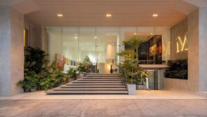 A modern hotel entrance with glass doors, a staircase leading inside, and indoor plants. - M Village Hotel Lý Tự Trọng, a brand of Modern Village Lifestyle (Ho Chi Minh City)