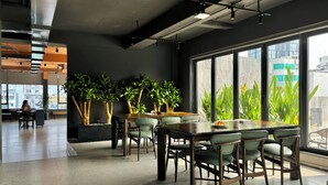 A modern office space with a large table and chairs, potted plants, and large windows offering views of buildings. - M Village Hotel Lý Tự Trọng, a brand of Modern Village Lifestyle (Ho Chi Minh City)