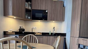 A modern kitchen with wooden cabinets, a Bosch microwave, and a dining area with wooden chairs. - Magnificent new 60m2 apartment in an exceptional location! (Samoëns)
