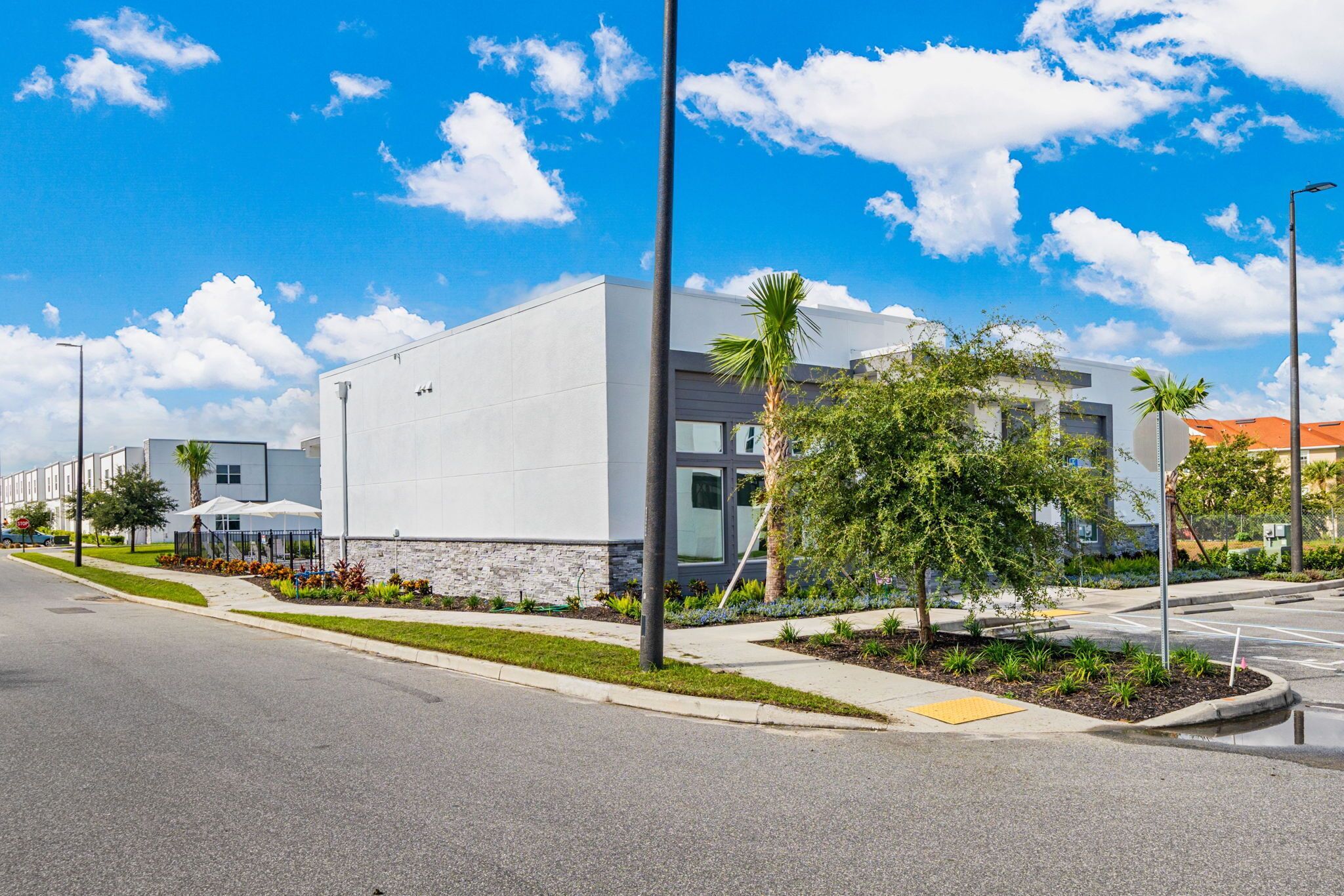 A modern building with a flat roof, large windows, and a paved parking area.