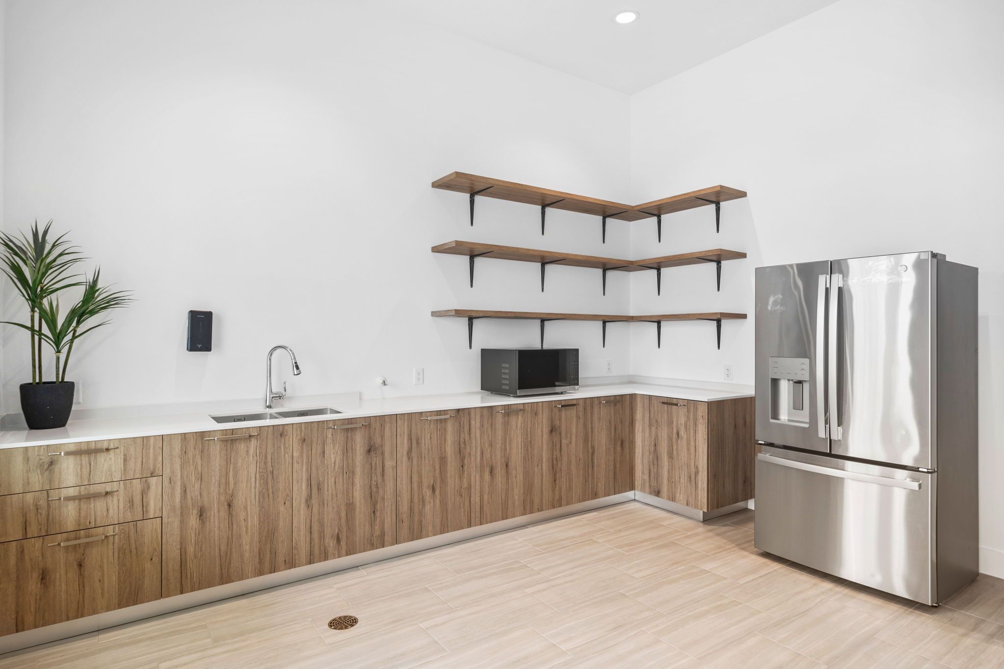 A modern kitchen with a stainless steel refrigerator, wooden cabinets, and built-in shelves.