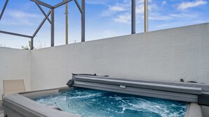 Un bain à remous doté d’un panneau de commande, entouré d’un mur blanc et de poutres métalliques.