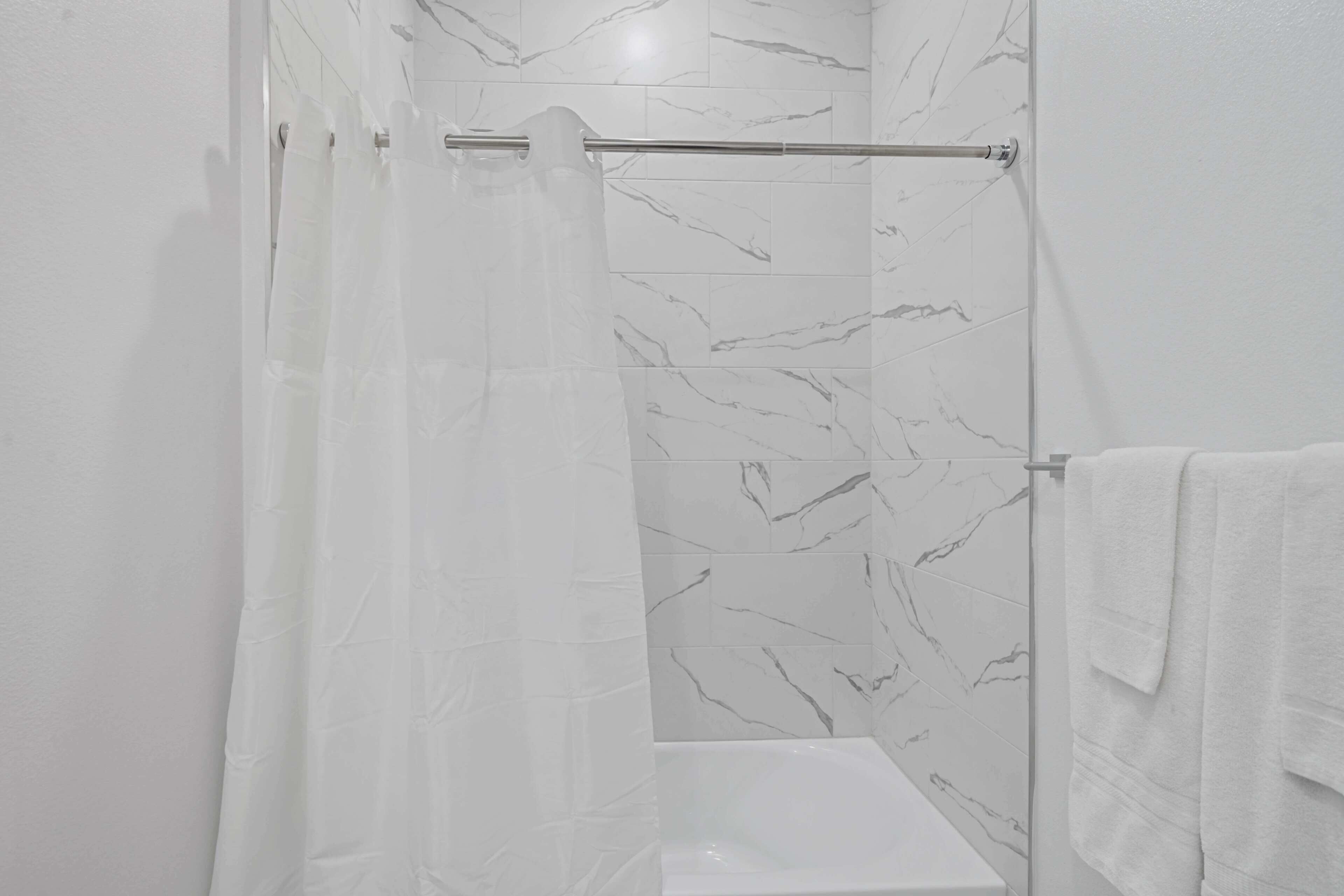 Une salle de bain avec un rideau de douche, une baignoire et un porte-serviettes.