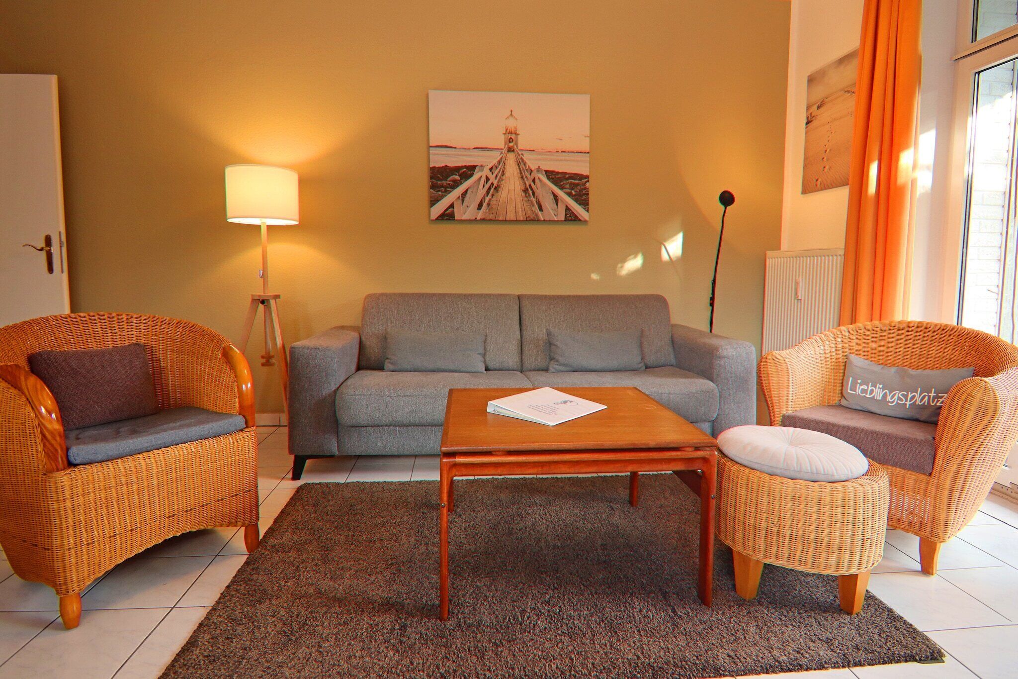 A living room with a sofa, two wicker chairs, a coffee table, a lamp, and a painting on the wall.