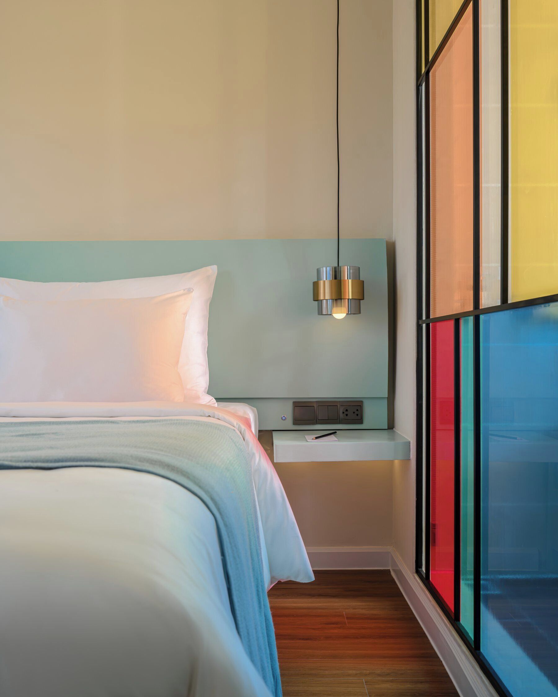Una habitación de hotel moderna con una cama, una mesita de noche y una lámpara de pared.
