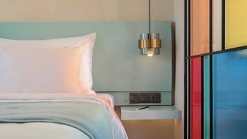 Una habitación de hotel moderna con una cama, una mesita de noche y una lámpara de pared.