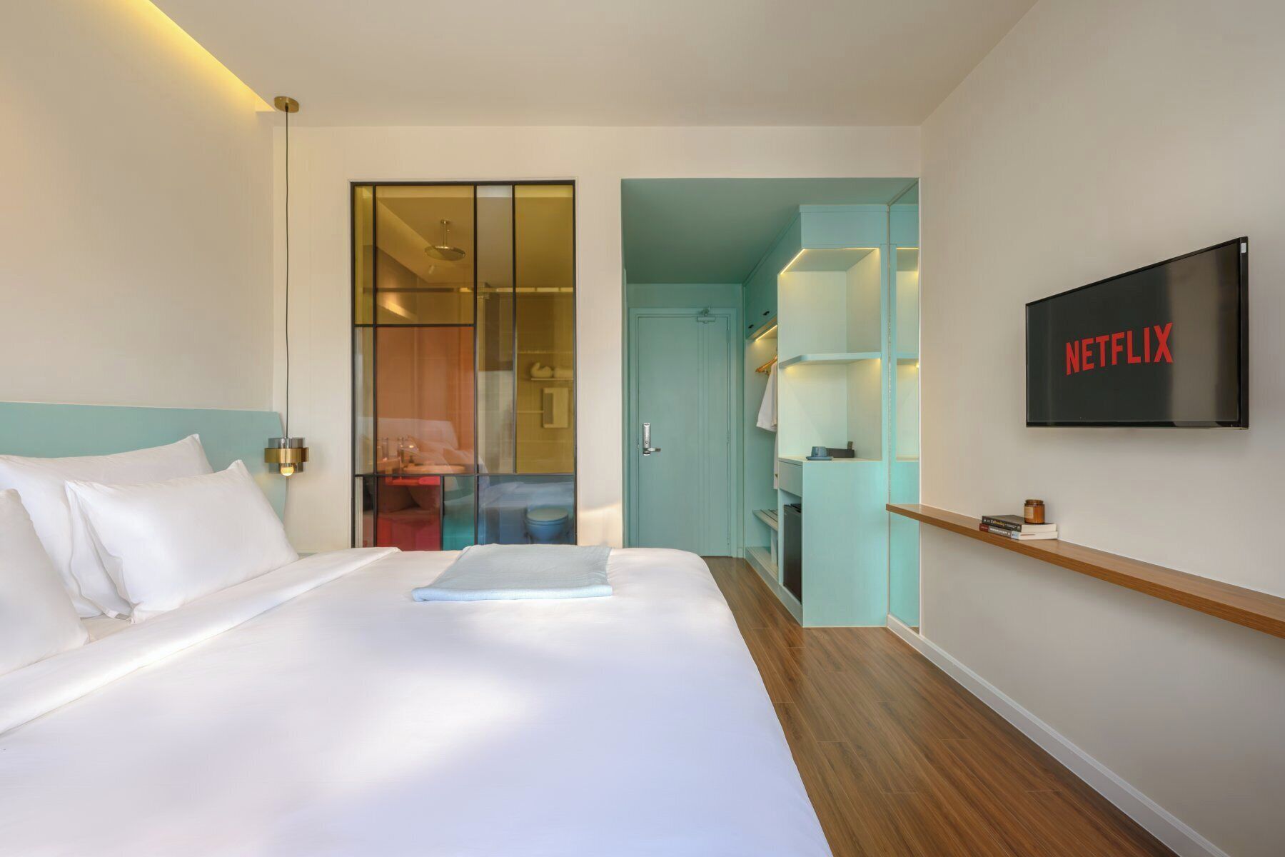 Een hotelkamer met een bed, een aan de muur bevestigde televisie en een deur naar een badkamer.