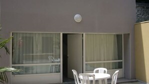 Een gebouw met een modern ontwerp, met grote ramen en een balkon met witte kunststof stoelen.