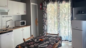 A compact kitchen with white cabinets, a microwave, and a dishwasher. There's a dining table with chairs and a floral tablecloth. The room has a wooden ceiling and a window with a floral curtain. - Chalet/Spa and private lake (CHALABRE)