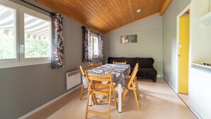 A dining area with a wooden ceiling, a table with chairs, a sofa, and a yellow door. - Chalet/Spa and private lake (CHALABRE)